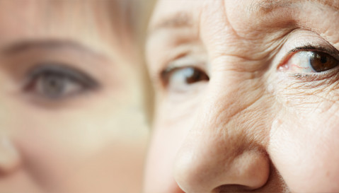 A close up of the eyes of an elderly woman with a close up of a younger woman in the background