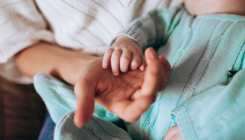 parent holding baby's hand