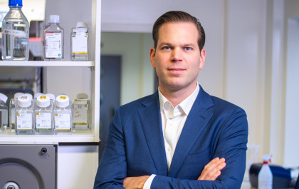 Daniel de Boer wearing a blue suit stands with arm crossed in a laboratory setting.