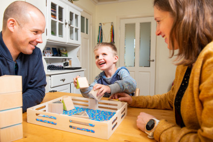 Young boy, living with Leber Congenital Amaurosis, playing a game for blind kids with his parents