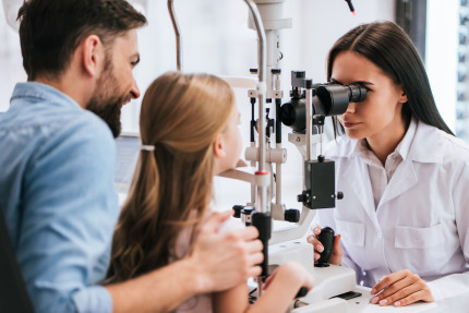 Young girl gets her eyes tested by a clinician
