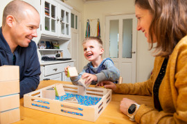 Young boy, living with Leber Congenital Amaurosis, playing a game for blind kids with his parents